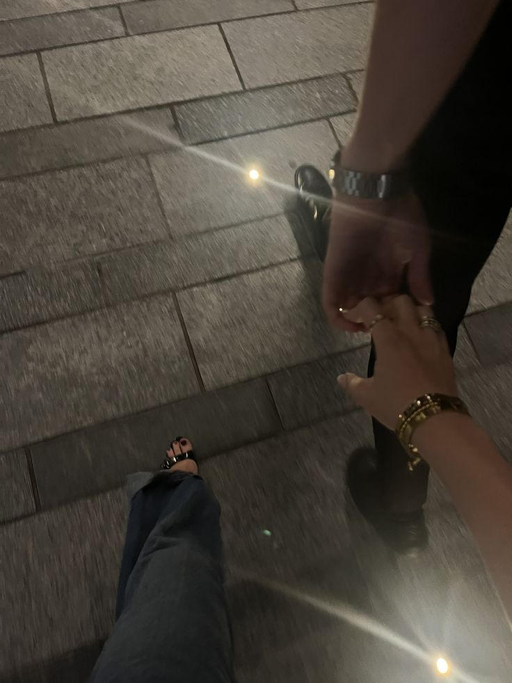 Two people holding hands while walking at night